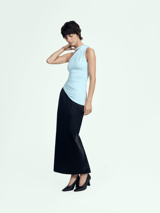 Woman wearing a light blue sleeveless top and black skirt on a white background