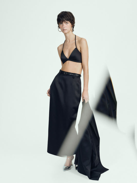 Woman wearing a satin bra top and black satin skirt on a white background