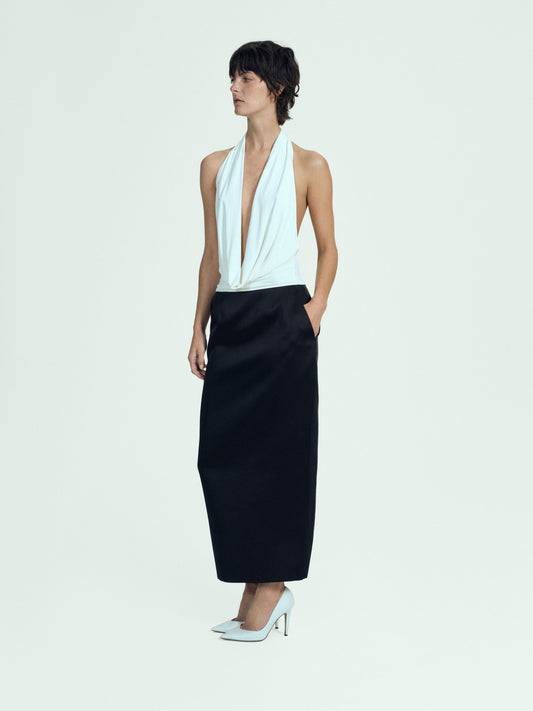 Woman wearing a white halter top and black satin skirt on a white background