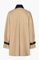 Beige mini trench coat with black leather collar and belted cuff accents on a white background