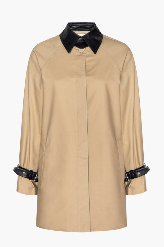 Beige mini trench coat with black leather collar and belted cuff accents on a white background