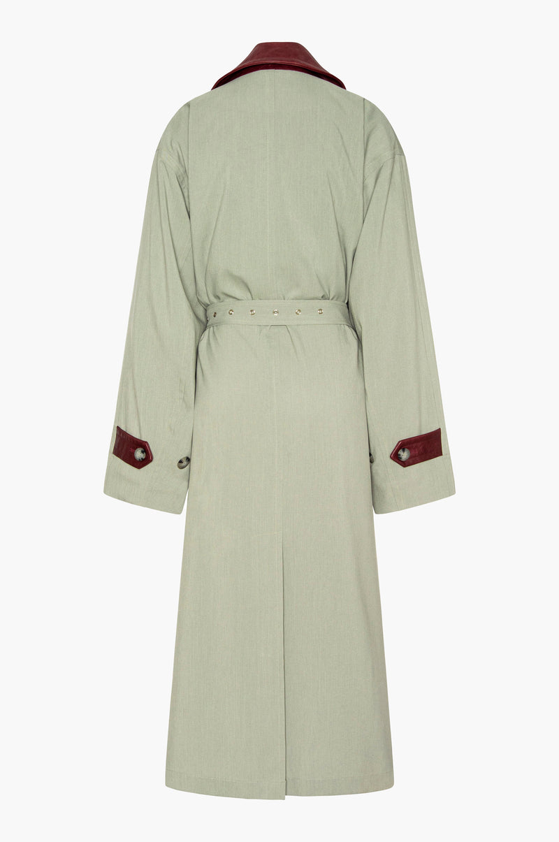 Seafoam green trench coat with a burgundy leather collar and cuffs on a white background