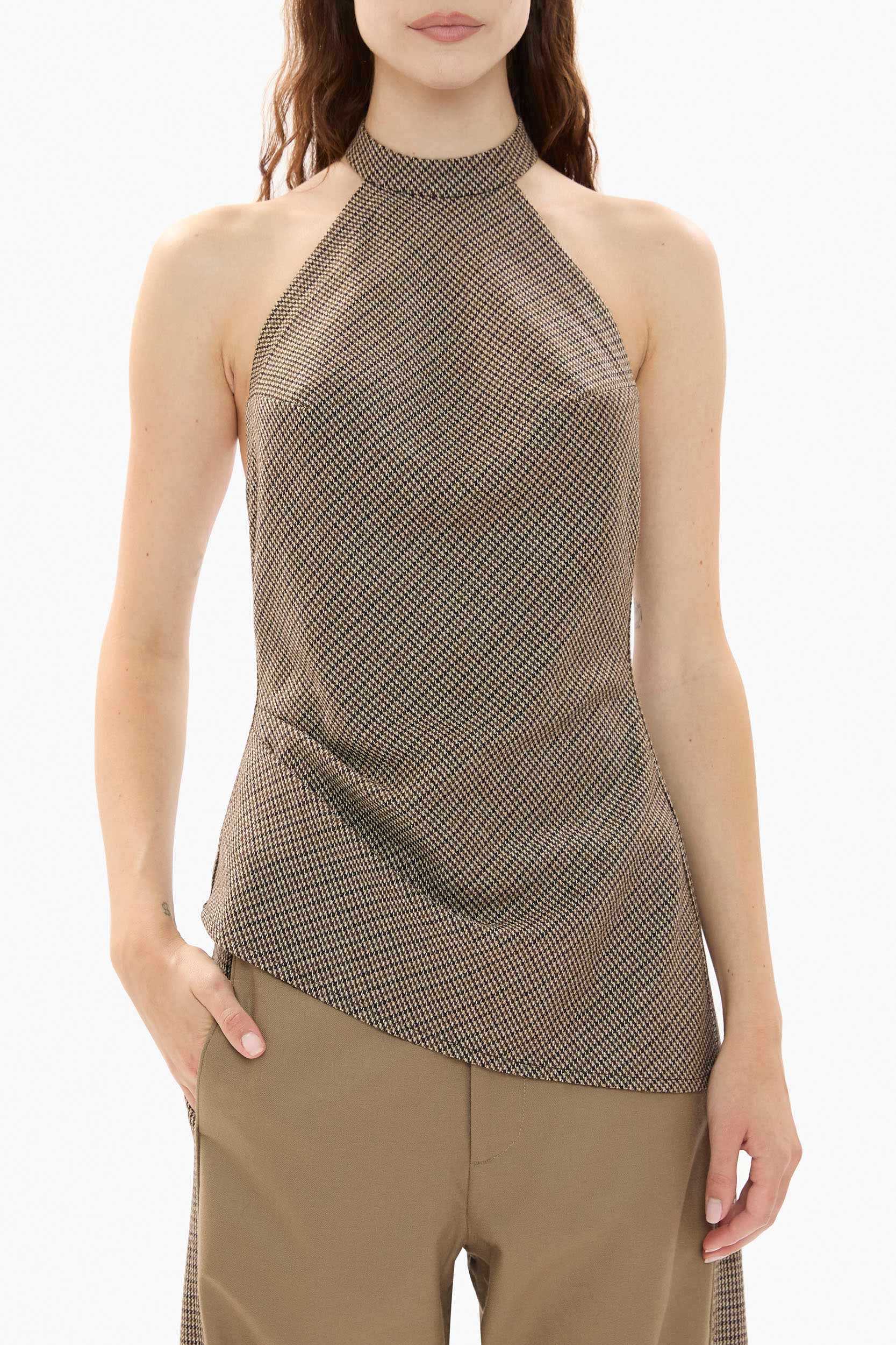 Woman wearing a houndstooth halter top and beige pants on a white background