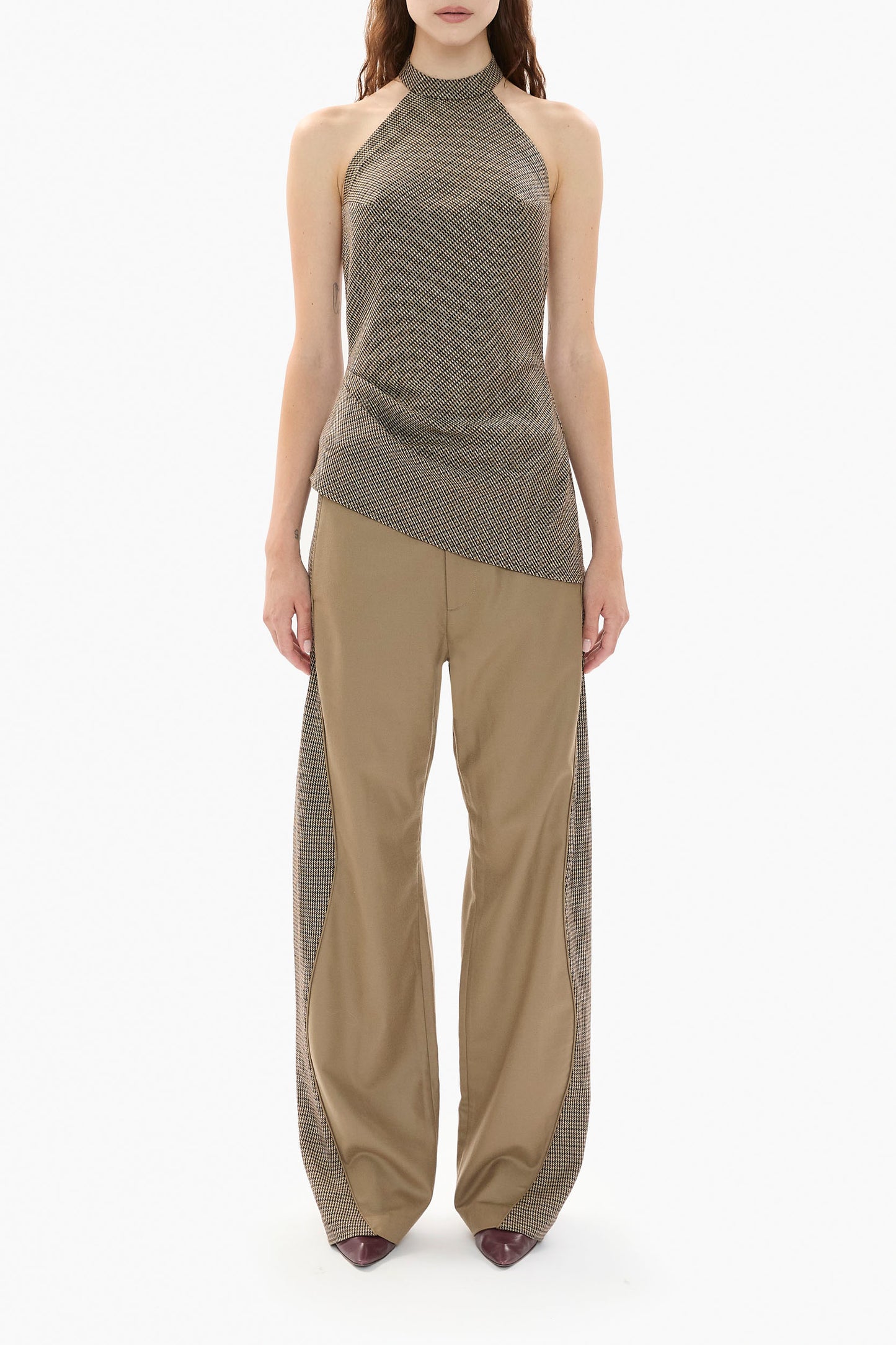 Woman wearing a brown houndstooth halter top and beige pants on a white background