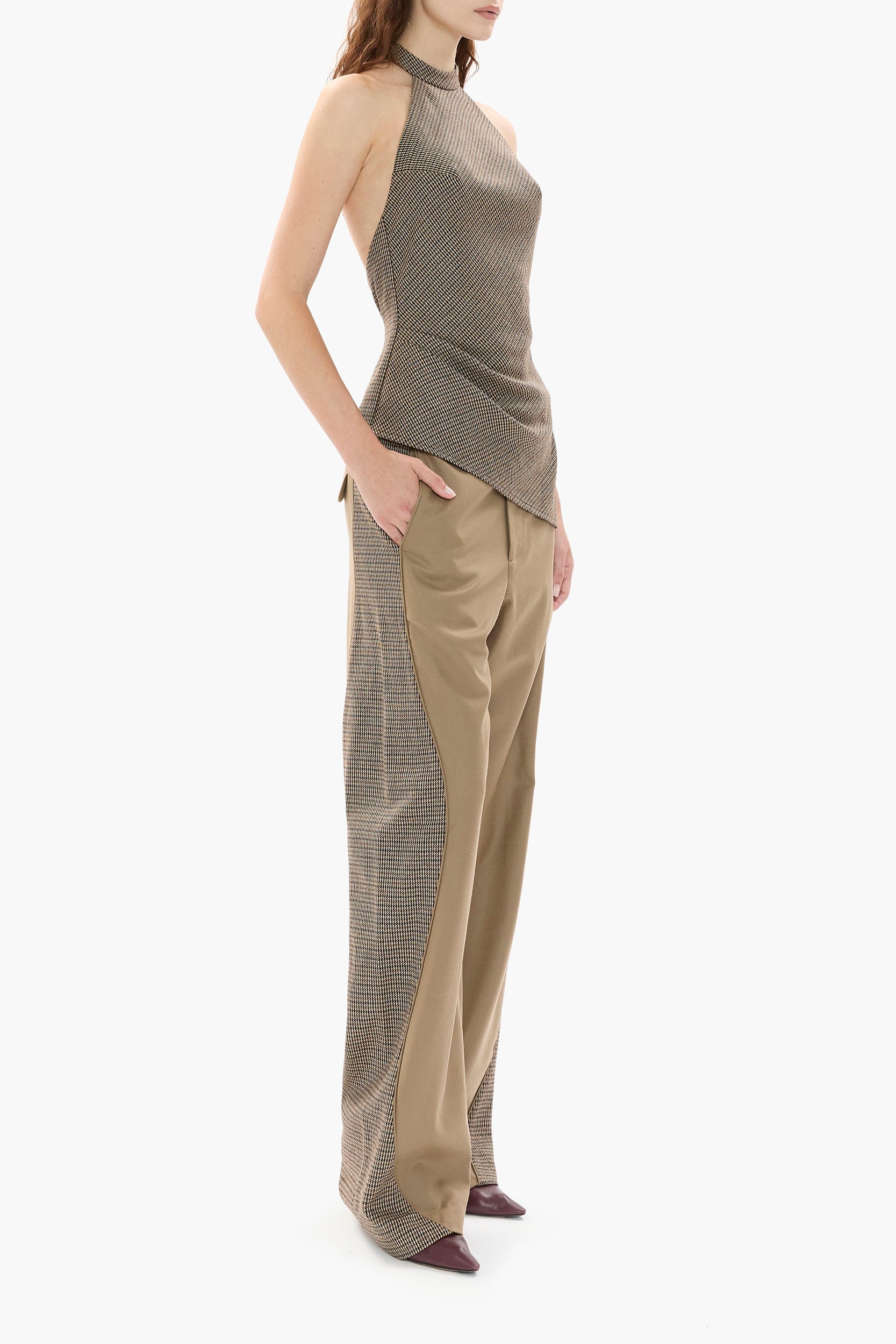 Side profile of woman wearing a houndstooth halter top and wide-leg pants on a white background