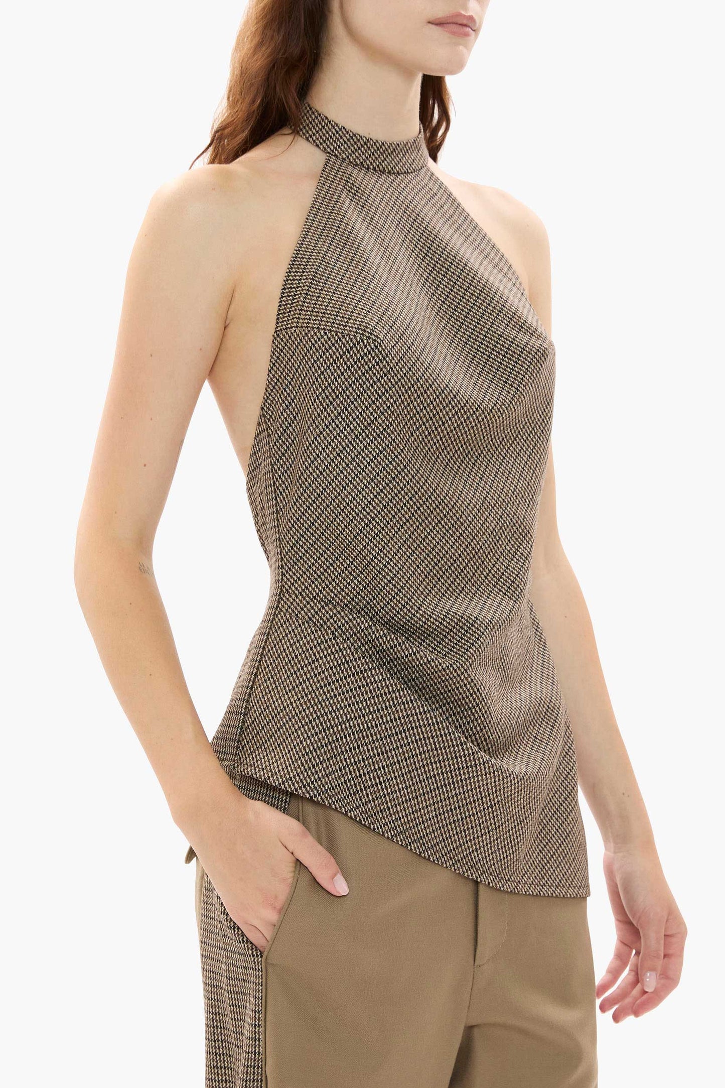 Woman wearing a houndstooth halter top and beige pants on a white background