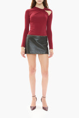 Person wearing a burgundy red long-sleeve top and black leather skirt on a white background