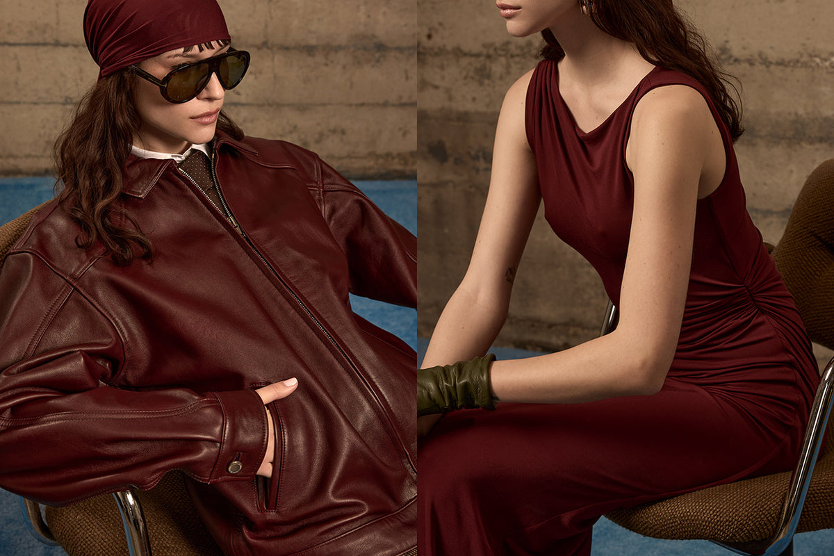 Mimchik Fall/Winter 2025 editorial campaign image featuring a model in a burgundy leather jacket and oversized sunglasses, alongside another model in a burgundy dress and green leather gloves, seated against a concrete wall.