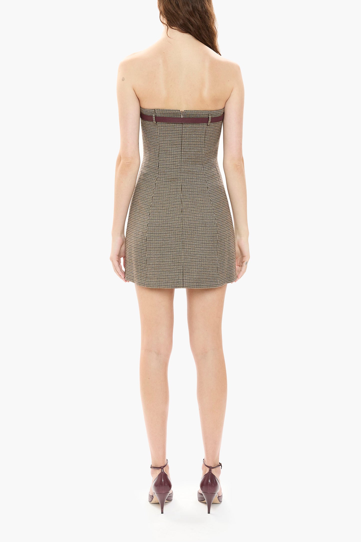 Woman wearing a strapless brown houndstooth mini dress on a white background