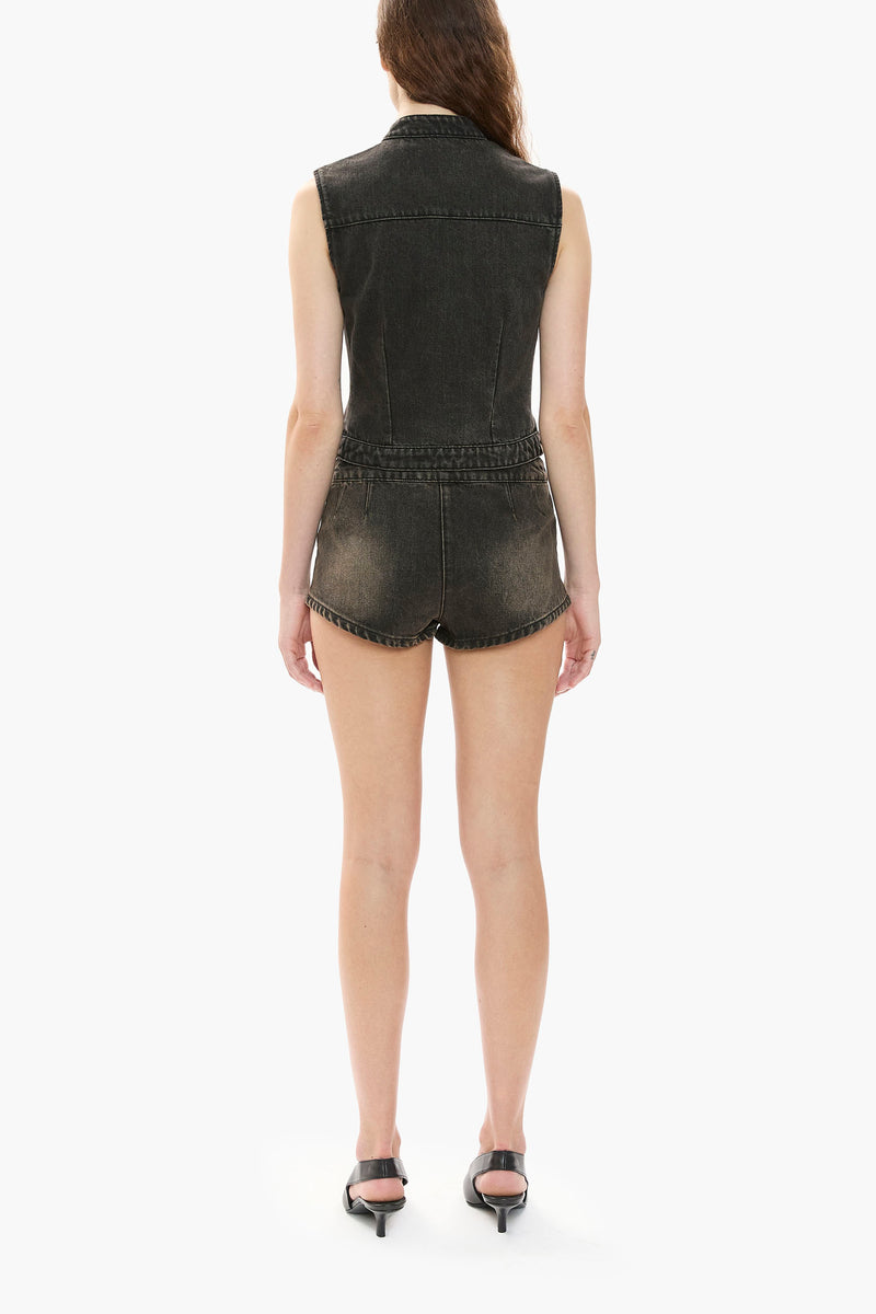 Person wearing a black denim vest and shorts on a white background