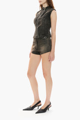 Woman wearing a black sleeveless denim vest and shorts on a white background