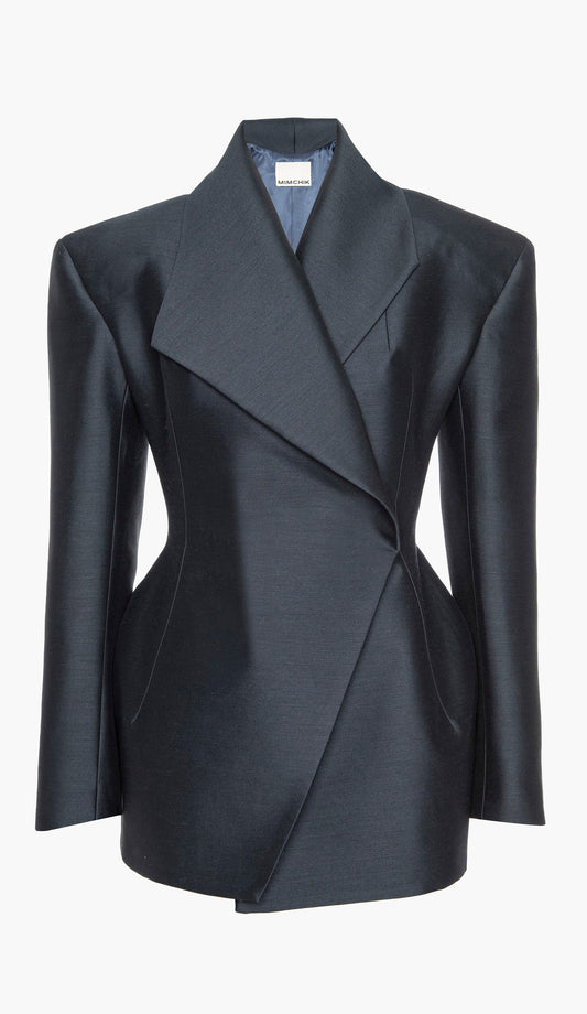 A navy blue silk wool blazer with an hourglass silhouette, asymmetrical shawl collar, and cinched waist on a white background