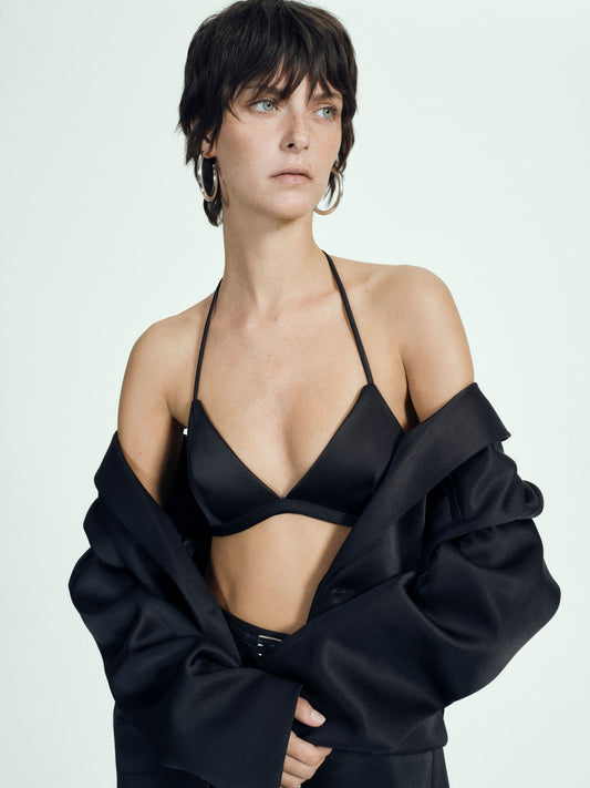 Woman wearing a black bra and black satin blazer on a white background