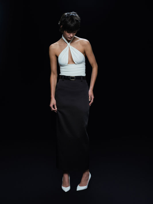 Woman wearing a white halter top and black skirt on a black background