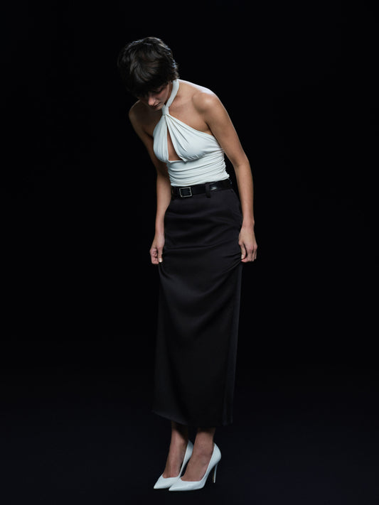 Person wearing a white top and black skirt on a black background