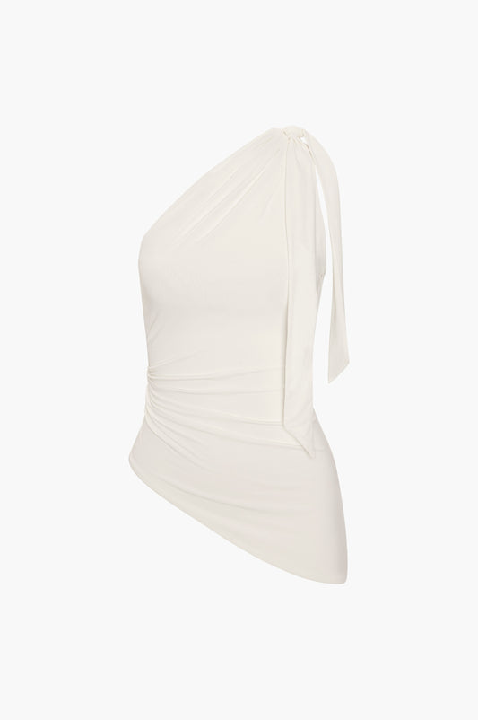 White one shoulder top on a light beige background