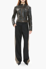 Person wearing a dark brown leather jacket and black pants on a white background