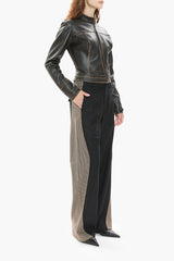 Person wearing a dark brown leather jacket and black pants on a white background