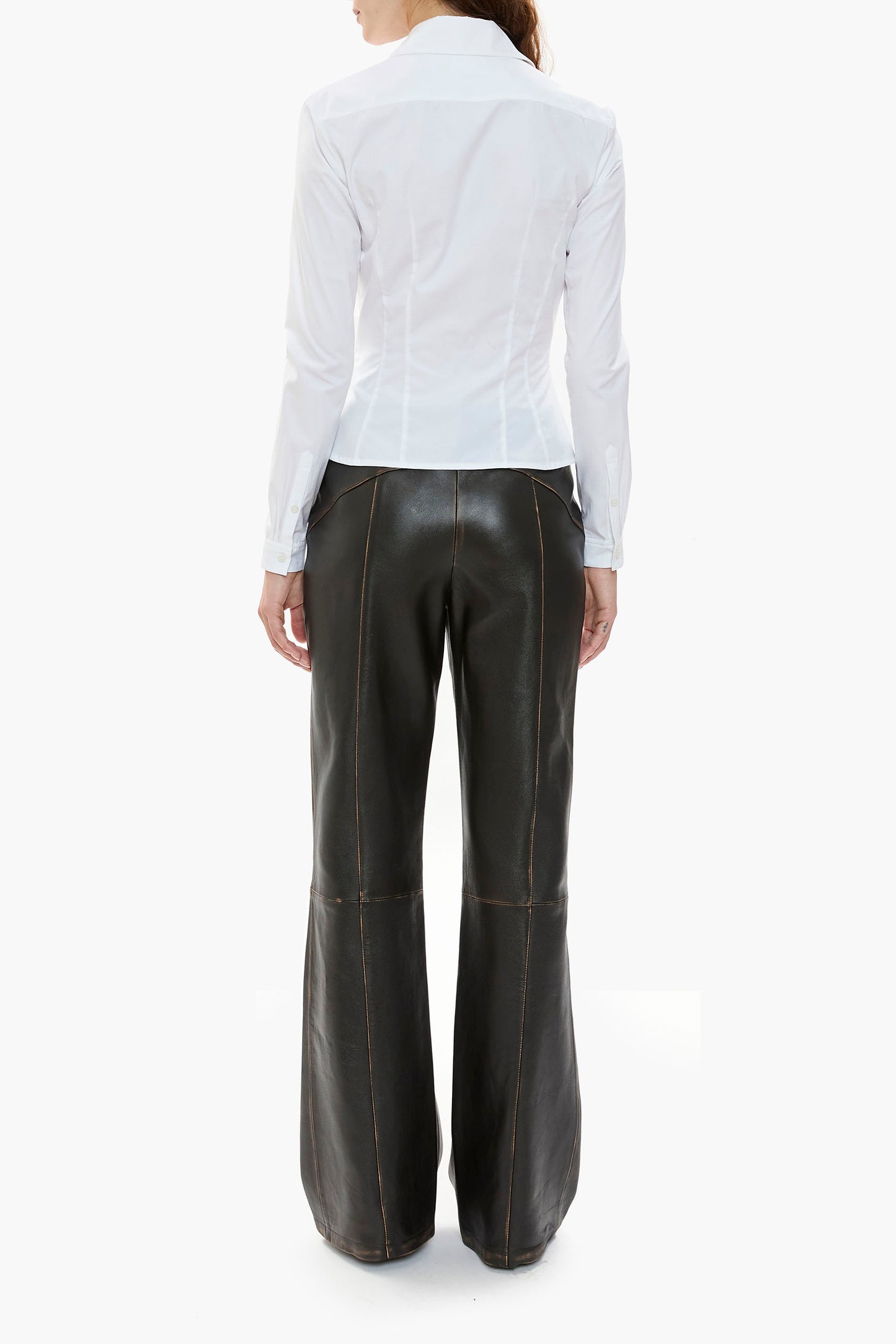 Person wearing a white shirt and dark brown leather pants on a white background