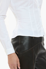 Person wearing a white shirt and dark brown leather pants on a white background