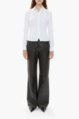 Person wearing a white shirt and dark brown leather pants on a white background