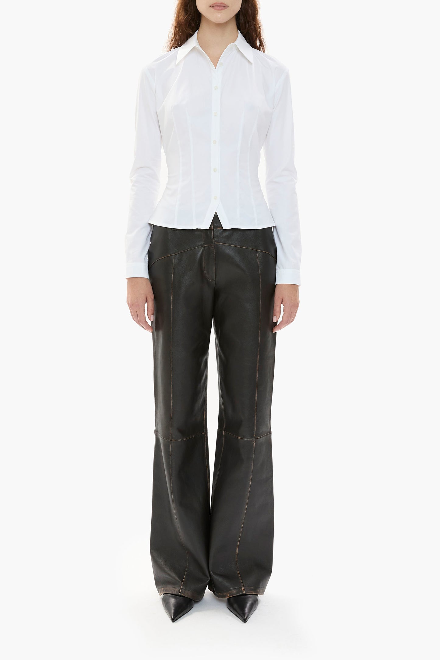 Person wearing a white button-down shirt and black leather pants on a white background