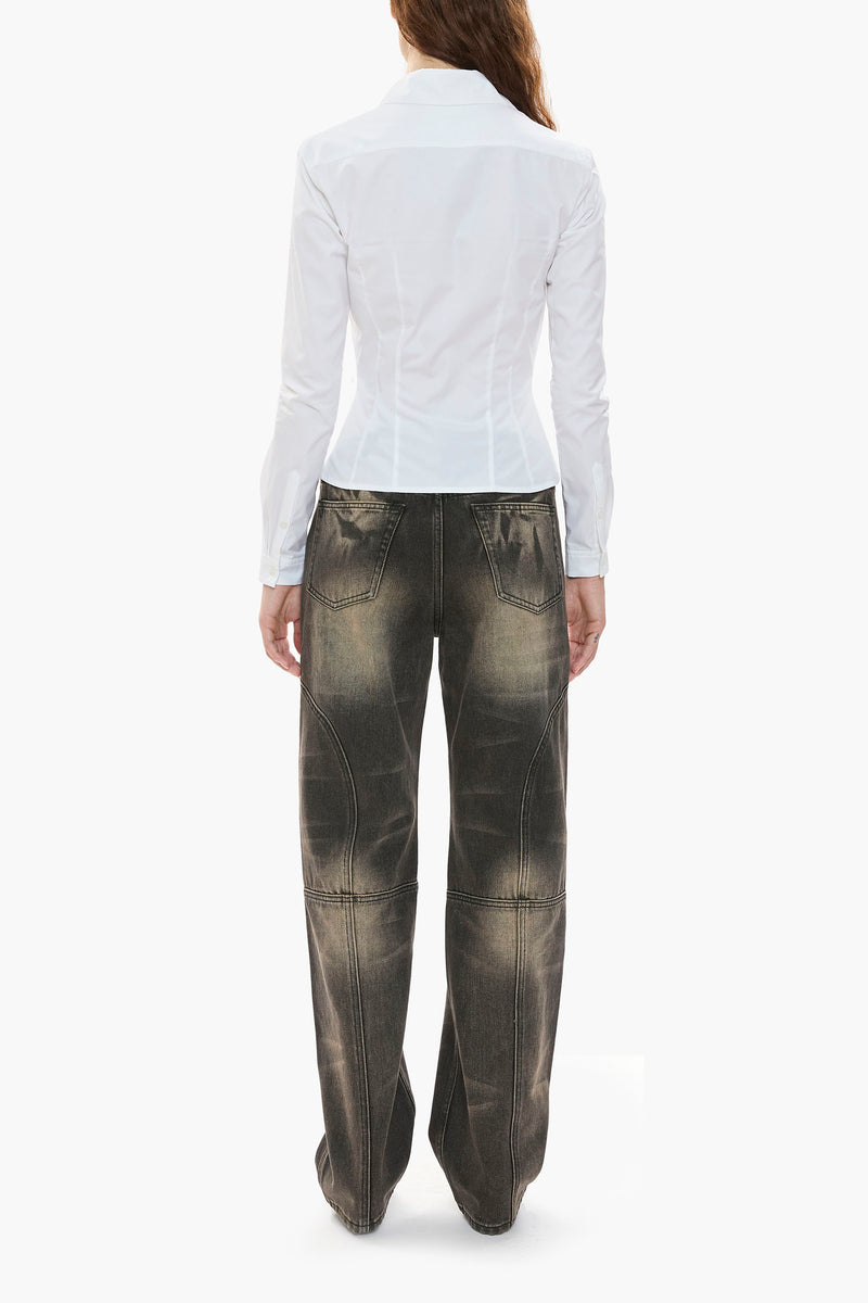 Person wearing a white blouse and distressed black wash jeans on a white background