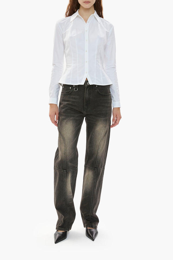 Person wearing a white shirt and distressed black wash jeans on a white background