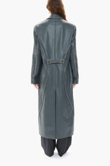 Person wearing a long dark blue leather coat on a white background