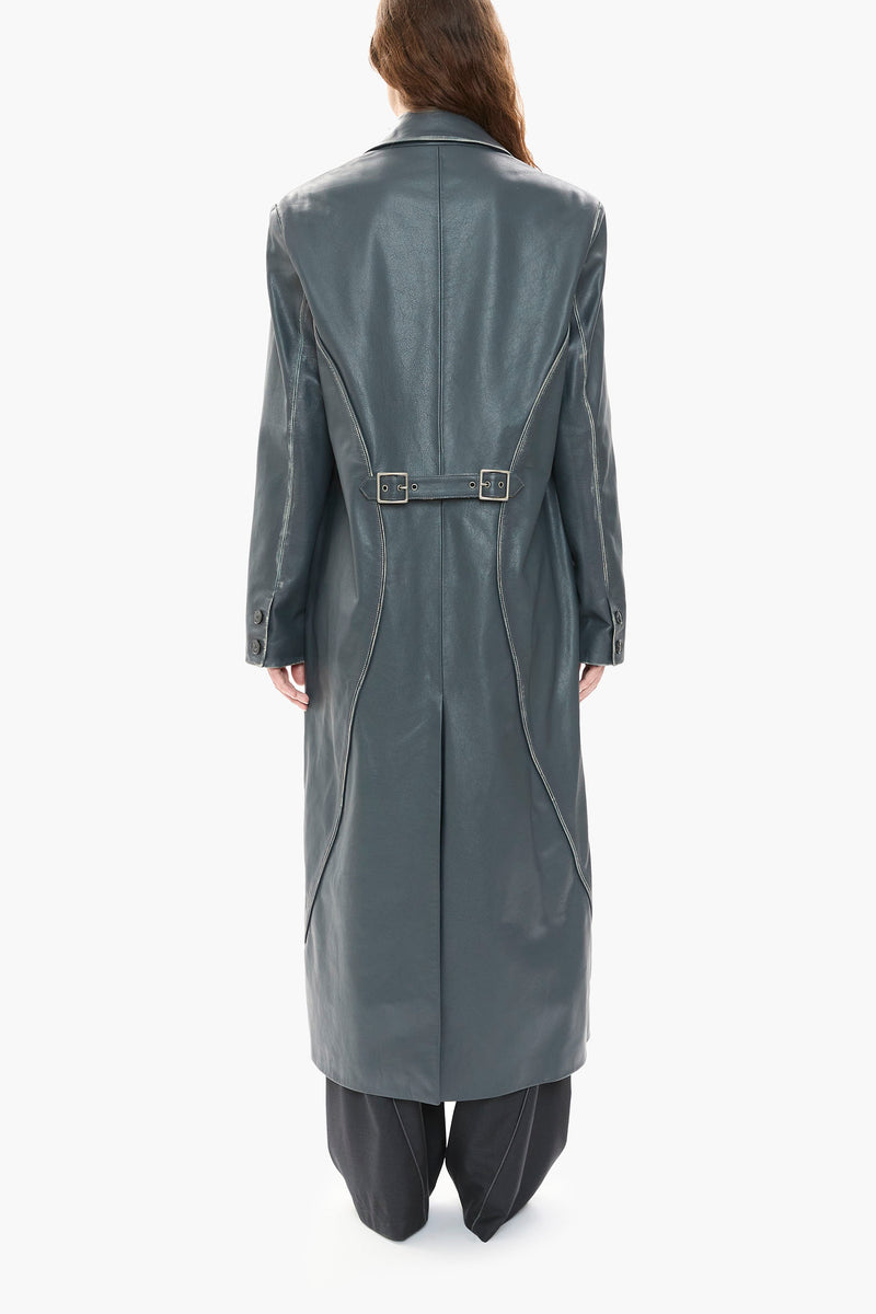 Person wearing a long dark blue leather coat on a white background