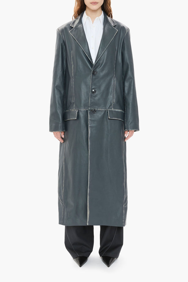 Person wearing a long dark blue leather coat on a white background