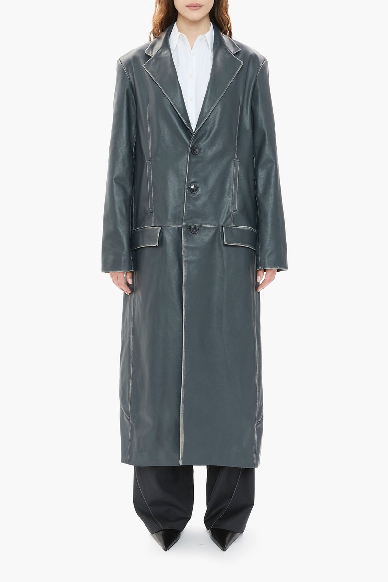 Person wearing a long dark blue leather coat on a white background