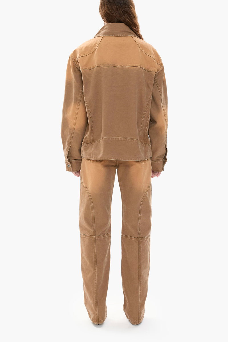 Person wearing a light brown canvas jacket and pants on a white background
