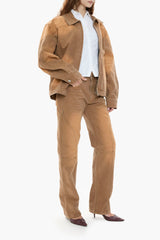 Person wearing a light brown canvas jacket and pants with a white shirt on a white background