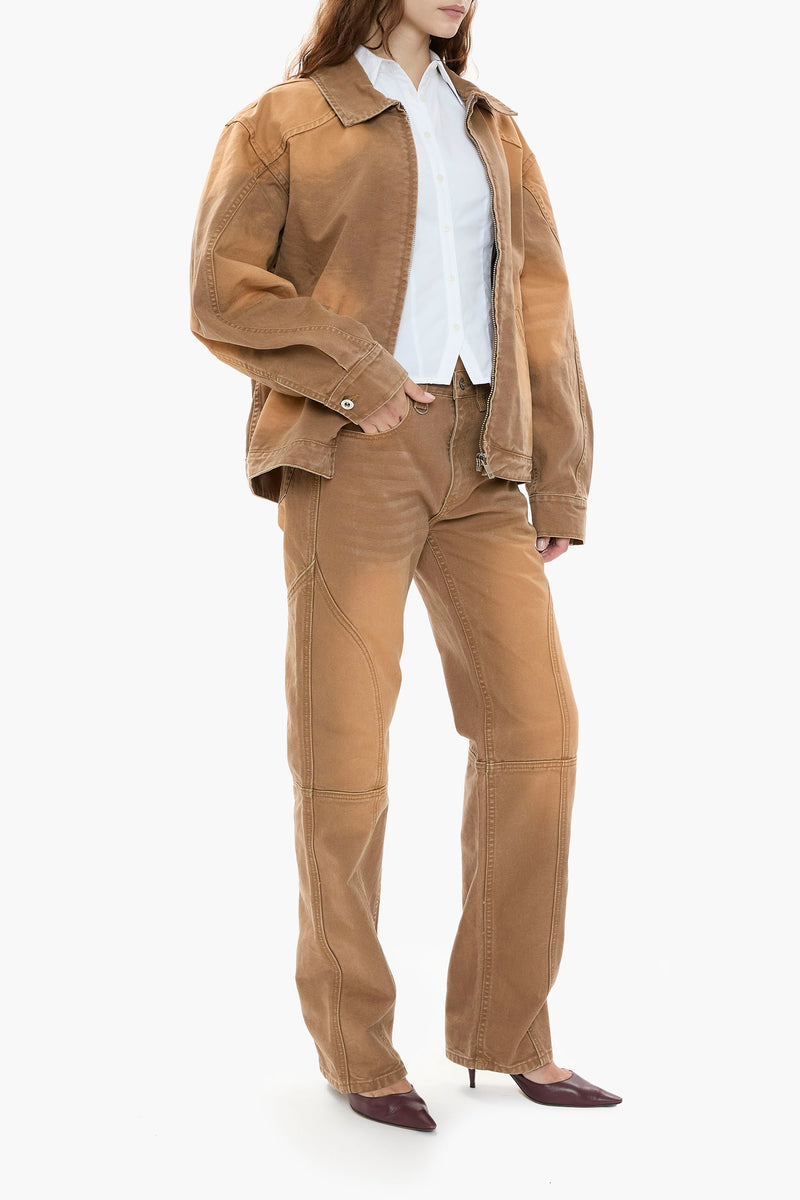 Person wearing a light brown canvas jacket and pants with a white shirt on a white background