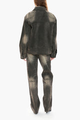 Person wearing a black distressed denim jacket and jeans on a white background