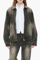 Person wearing a black distressed denim jacket and jeans on a white background