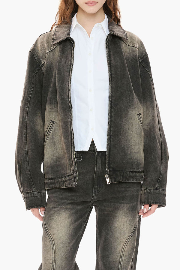 Person wearing a black distressed denim jacket and jeans on a white background