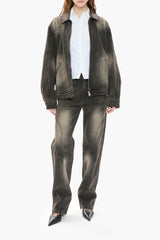 Person wearing a black distressed denim jacket and jeans on a white background